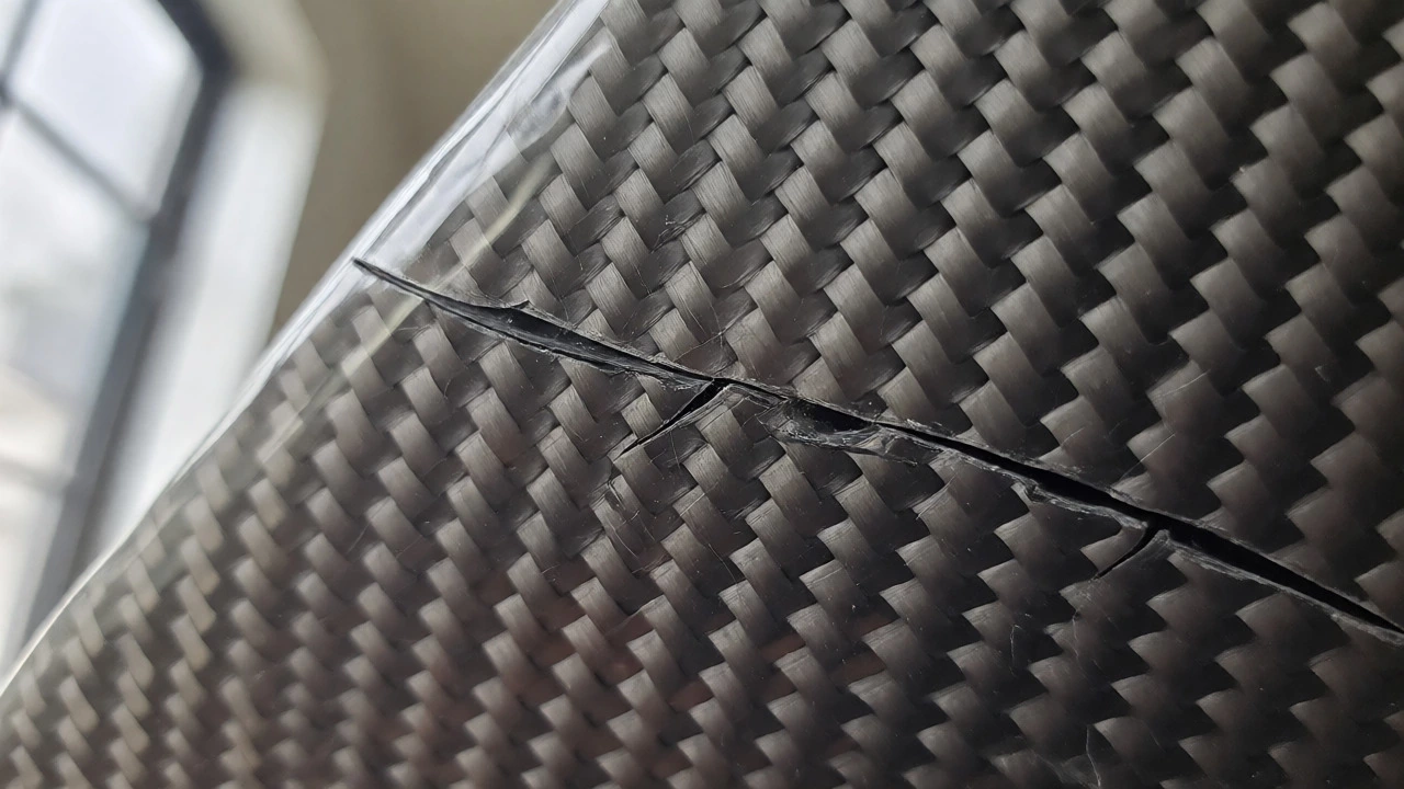 Spiderweb cracks on a carbon fiber car part surface